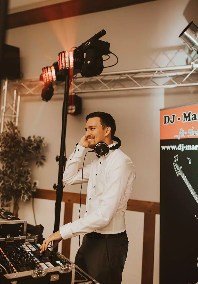 DJ Marcel ist auf einer Hochzeit in Bremen und Oldenburg zusehen und lächelt die Gäste an.